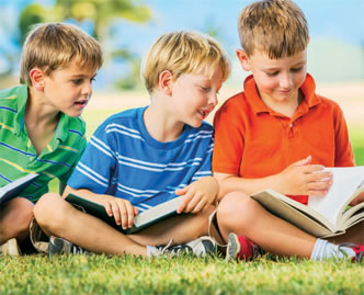 three young boys reading outside